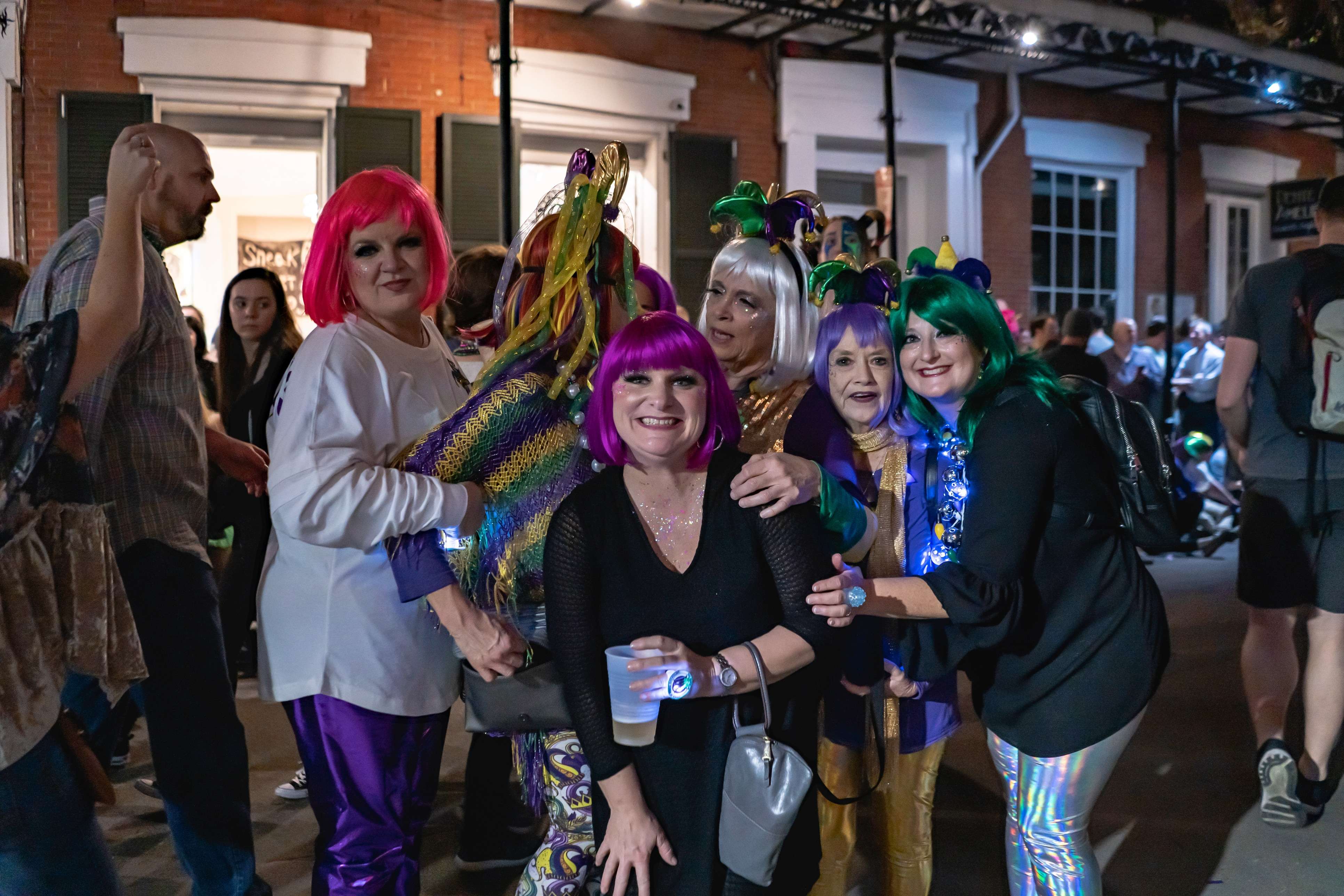 A group of friends wear New Orleans Mardi Gras costumes at a parade
