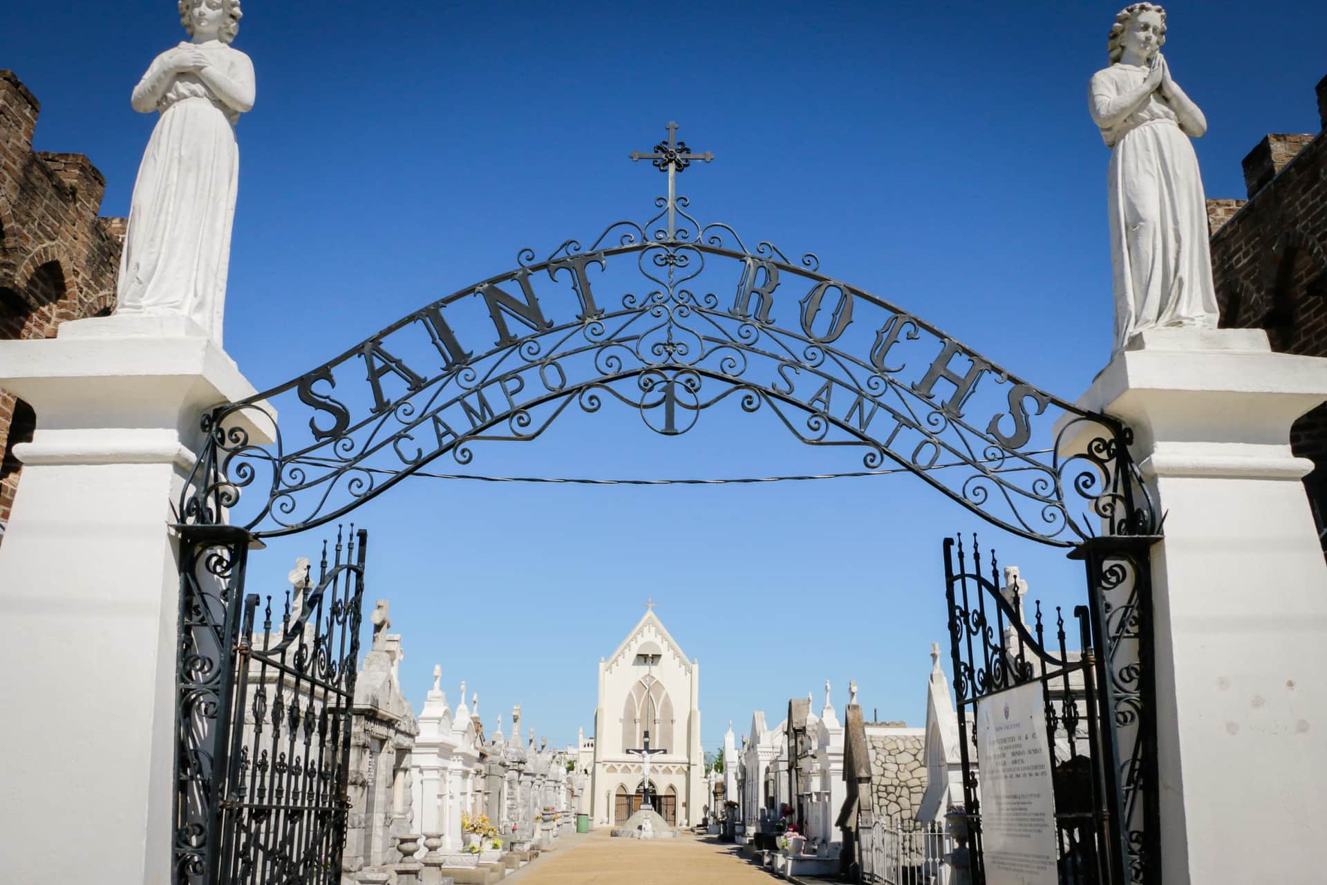A haunted New Orleans cemetery with a wrought iron fence gate.